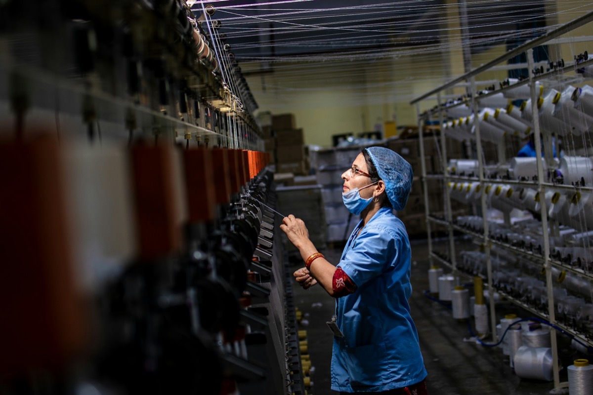 Factory worker operating a yarn winding machine on a manufacturing shop floor